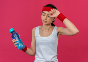 young fitness woman sportswear with headband holding bottle water looking tired standing pink wall 141793 48843